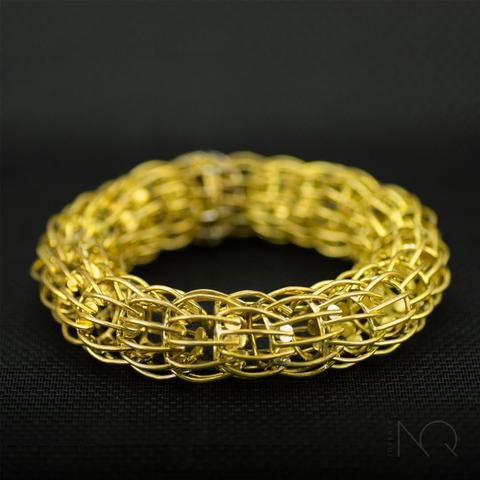 foto de una pulsera de eslabones  redondos con muchos palos a modo de brazos color dorado