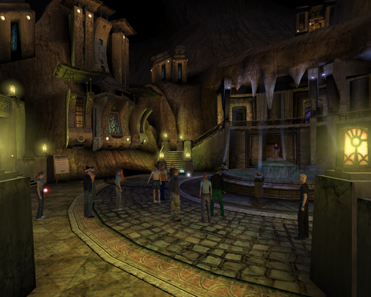 A plaza with a fountain, inside an underground city. The buildings are half-buried in the rocks, and lit by yellow and orange lights. The windows are made of colored stained glass. A dozen or so explorers are gathered here.