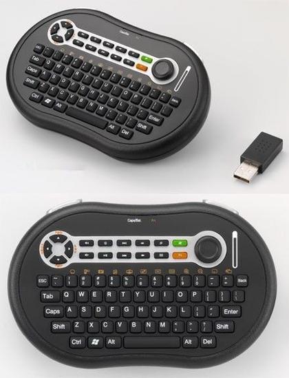 A kidney shaped thumb keyboard with analog stick for mouse control and a proprietary USB dongle.