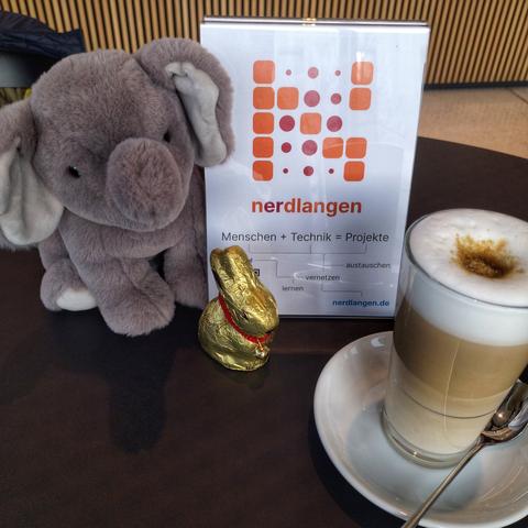 Unser Maskottchen, ein goldener Schokoladen-Osterhase und unser Schild auf einem Tisch. Und natürlich Kaffee.