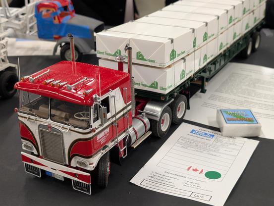 Cab over truck pulling a trailer with processed timber products wrapped in protective fabric.