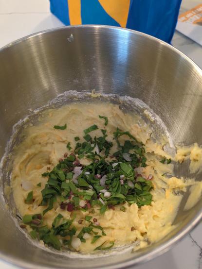 Mashed potatoes, eggs, cheese and a generous helping of chopped ramps in a metal mixing bowl