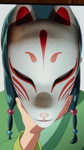 The character from an anime is holding a kabuki mask over her face. The mask has animal ears that could be a fox, a lion, a dog, or a cat. The eyes are slanted, which leads me to think it is a fox. There are red whisker like lines on the cheeks And a three stroke design on the forehead which seems to correspond to Kitsuné foxes, But I haven't seen this exact design in images.