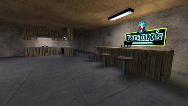 In this picture you can see a bar and in the background a kitchen. The bar has three stools attached to the floor with red seats. The bar is made of light wood. The same one that was used for the balcony. In the middle of the bar is a tap. Behind it hangs an illuminated sign for the beer "Beok's". Above the bar and the stools, a white-lit lampr is attached to the ceiling. The kitchen has an L-shape. It is also made of light wood. In addition, the kitchen consists of a set on the floor and one that is attached to the wall / ceiling. On the left side is a sink, above which is a white-lit lamp on the upper part of the kitchen. And to the right at the bend, is the stove. Above it is also a white-lit lamp. To the right of the kitchen you can see another hallway. This is on the map cs_militia in the game Counter-Strike 1.6.