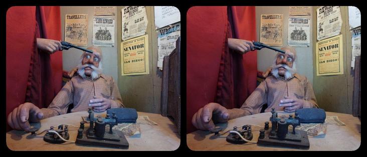 Telegraph operator at Enchanted Forest. A hand holding a pistol is coming in from some curtains on the left; operator looks worried.