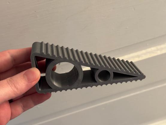 A dark gray triangle wedge with bumps on the top. The middle of the wedge is mostly hollow, but has two circles for additional support.