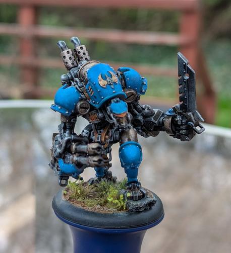 A painted mini of a steampunk robot from the game Warmachine, in blue, brass, and silver.