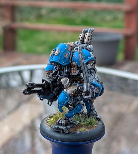A painted mini of a steampunk robot from the game Warmachine, in blue, brass, and silver.