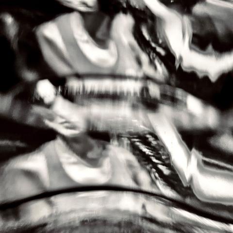A blurred, abstract image of a person's face and upper body, captured in monochrome with distorted lines and shapes.