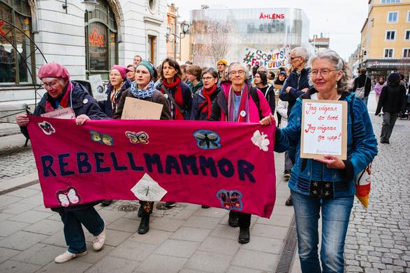 REBELMAMMOR group walking with the deep pink banner in the protest.