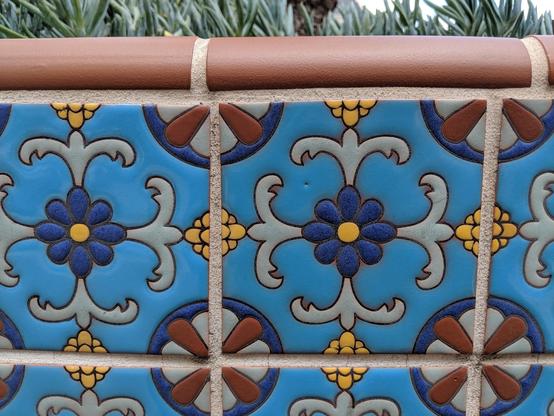 Alt Text: Image displays blue painted azulejo ceramic tile on a low wall surrounding a planted area in a courtyard.

Texte alternatif : L'image montre des carreaux de céramique azulejo peints en bleu sur un muret entourant une zone plantée dans une cour.

Texto alternativo: La imagen muestra azulejos de cerámica pintados de azul sobre un muro bajo que rodea un área plantada en un patio.
