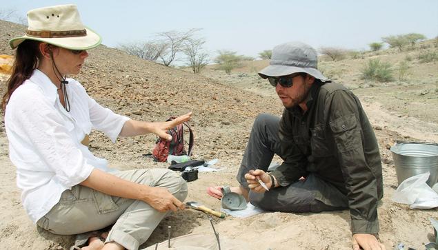 Sonia Harmand and a male archaeologist working on a site. She is a white woman with dark hair.