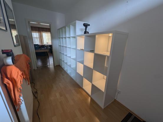 Angled view onto two Kallax shelves from the right. The front one has every other compartment lit up by an invisible spot light