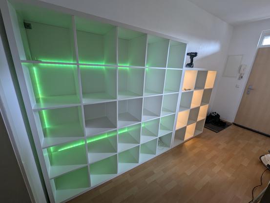 View on the same Kallax shelves from the other side. The compartments are lit in green lights by an indirect LED band on the backside of the shelf