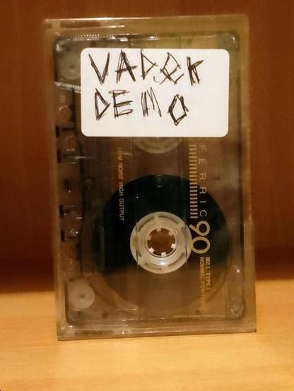 a translucent audio cassette with the manufacturer's markings still readable in a translucent case with a small sign, having "Vadok Demo" handwritten on it