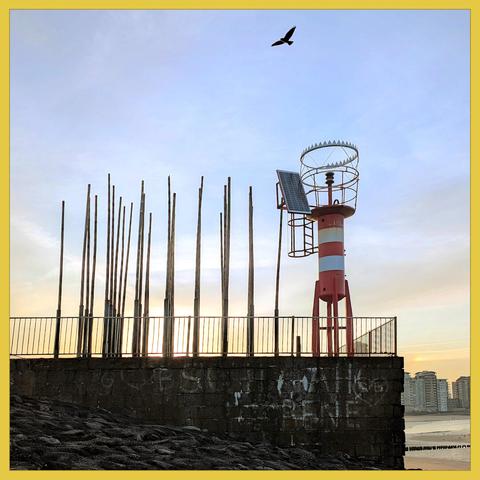 on a WWII bunker stands a serie of bamboo pipes and a harbour light. Through the sidewards openings in pipes blows the wind a hollow melody
