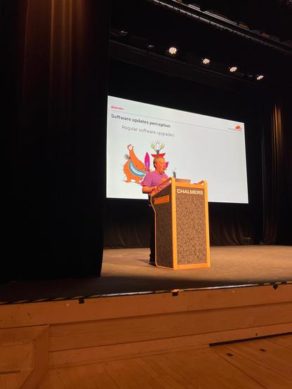 A person speaking in front of their slides, talking about Linux kernel updates.