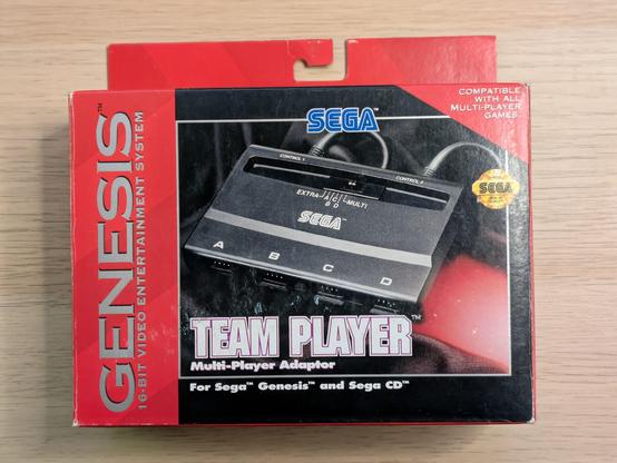A photo of the box of a Sega Genesis Team Player, an adapter for four controllers for the Sega Genesis console. It says "Compatible with all multi-player games".