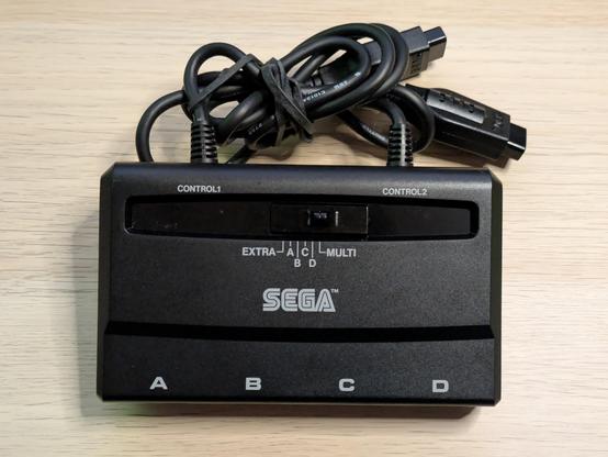A photo of the Team Player unit itself. It has a big slide switch on top with positions labeled Extra, A, B, C, D and Multi. The four ports on the front are labeled A, B, C and D, and it has two plugs protruding from the back - they are labeled Control 1 and Control 2.