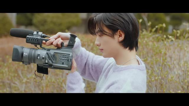 Hyunjin operating a video camera in the MV for Mixtape: On Track
