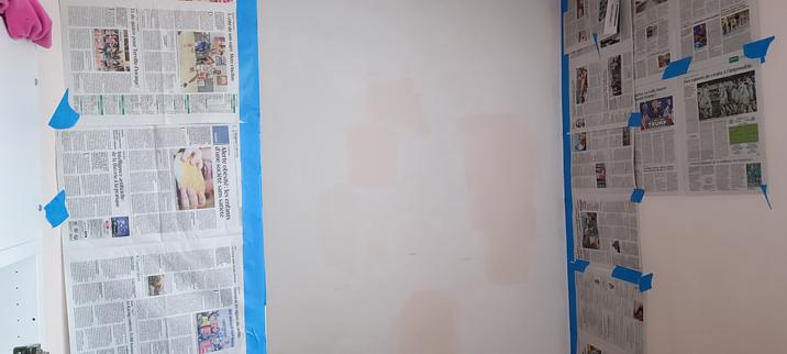 Mur blanc entouré de deux autres murs, sur lesquels j'ai mis des papiers journaux collés avec du scotch bleu.