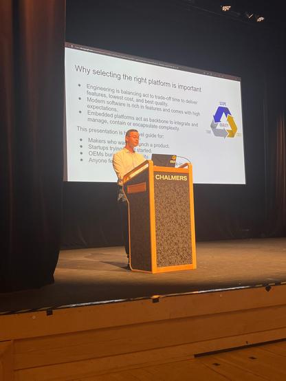 A person speaking at a lectern about embedded software development and open source.