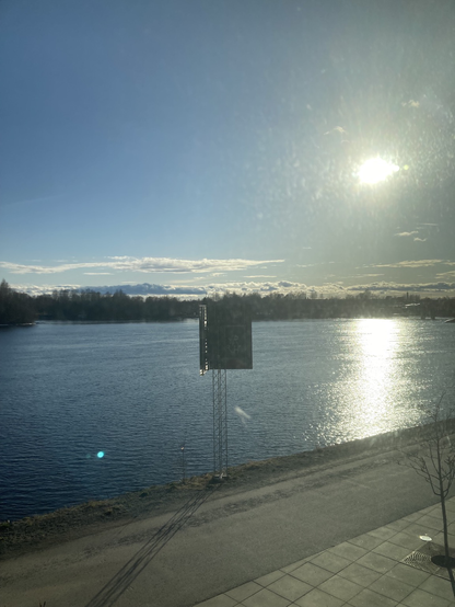 Foto ut genom fönstret, soligt med utsikt över promenadstråk och Umeälven. Just nu 11grader och sol