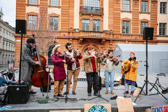 The music group playing various instruments and singing on the stage.