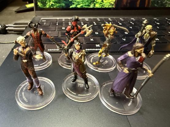 BG3 miniatures of seven of the companions: Wyll, Karlach, Lae'zel, Withers aka Bonedaddy, Astarion, Shadowheart and Gale of Waterdeep.