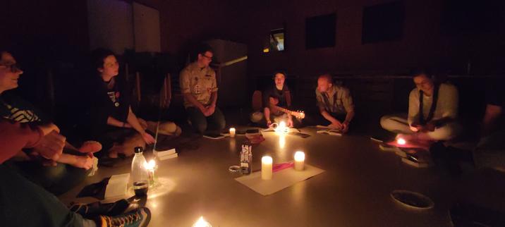 Menschen sitzen im Kreis. In der Mitte sind Kerzen.