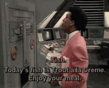 A sharp dressed kid form descended from cats, ordering lots of fish from a spaceship meal dispenser