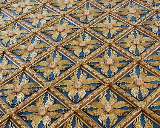 Closeup of the starburst pattern in the ceiling. Each is a cherub's face, with eight stylised wings surrounding it.