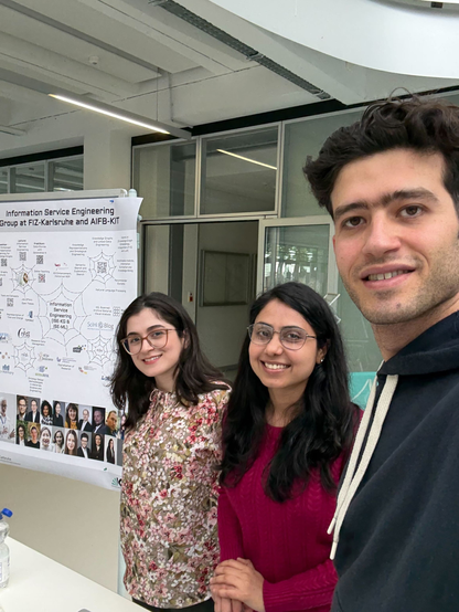 fromn left to right: Marzieh Moghaddam, Gunjan Singh and Ebrahim Norouzi standing next to our poster at the WiWi Modulcafé in the foyer of the KIT Mathematics building.