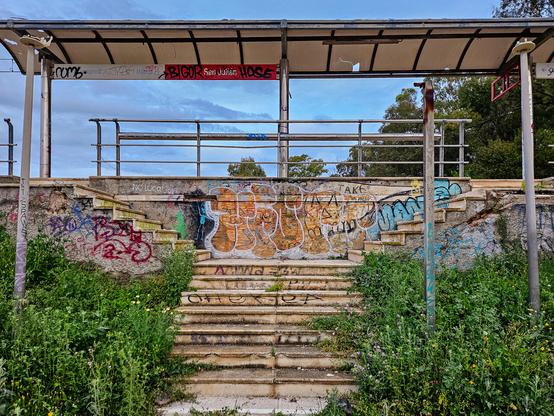 A staircase surrounded by weeds, leading up to the same platform as the previous photo. The station name, San Julián, is visible.