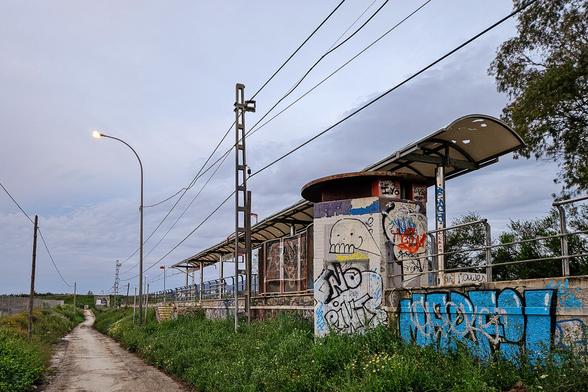 View of the same station from outside. A dirt track leads into the distance parallel to the railway.