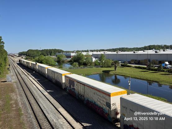Line of colorful refrigerated boxcars with graffiti on a passing train.