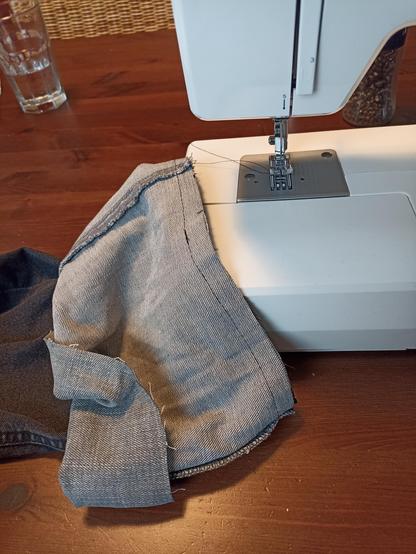 sewing machine and next to it are two denim pieces, a dark gray and a light gray one. it looks like they are going to be sewn together