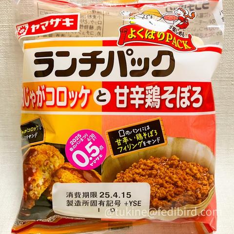 ヤマザキの「ランチパック 肉じゃがコロッケと甘辛鶏そぼろ」のパッケージ。鮮やかな赤とオレンジのデザインで、サクサクした衣のじゃがいもコロッケと、艶のある甘辛い鶏そぼろの写真が表示されている。