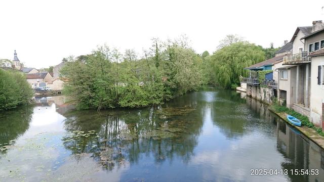 La Charente à Civray, entre bâtisses anciennes, arbres printaniers et clocher de l'église romane.