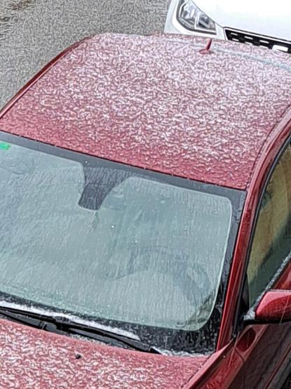 Imagen del techo de un coche granate cubierto por el granizo