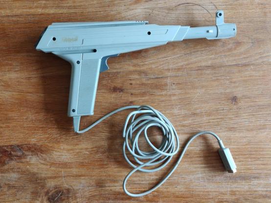 A side-on view of an Atari XG-1 light gun lying on a wooden table, pointing right. I secretly hankered after one of these after reading about it in the Atari BASIC Reference Manual. Having survived a war, my parents were resolutely against toy guns for children, so I doubt I ever even mentioned its existence to them. I didn't want to sully their perception of home computing as playfully scientific.