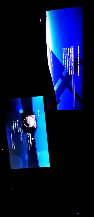 The photograph shot & composed in total darkness shows two screens displaying a user interface, likely from the KDE Desktop. The top screen has a blue background with white text, indicating a welcome message and system information, including the date "April 22, 2023." The bottom screen shows a music player interface on the second IPS LED panel with a track titled "The Division" by Pink Floyd, labeled as "Progressive Rock," with a progress bar indicating the song is at 00:44 out of 01:01. The word "Music" is visible on the right side of the bottom screen. The screens are angled and partially overlapped, with the top screen tilted to the right and the bottom screen tilted to the left. The background is dark, emphasizing the blue glow of the screens.