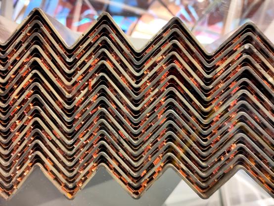 A stack of lead plates, each encased in 0.2 mm of stainless steel. The plates have been bent into a series of triangular waves and are spaced 4.2 mm apart. In the middle of each gap there is a thin copper sheet.