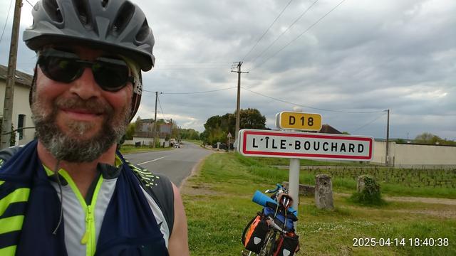 Gars souriant et vélo randonneuse posant à côté de l'entrée de l'Île Bouchard (Indre et Loire, parc naturel de Loire-Anjou-Touraine)