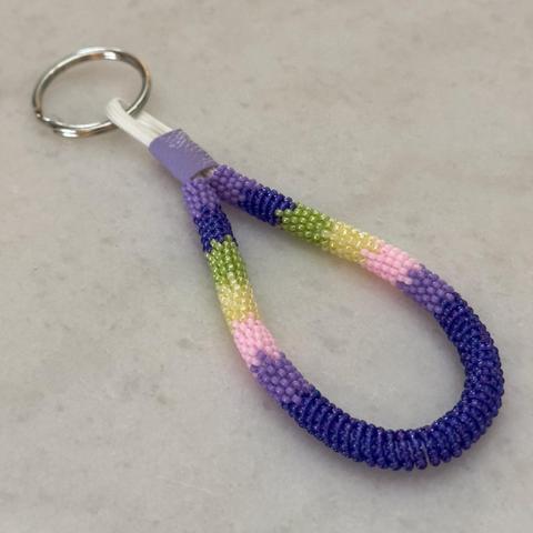A mini bead wrapped keychain in purple, blue, light pink, butter yellow, and green