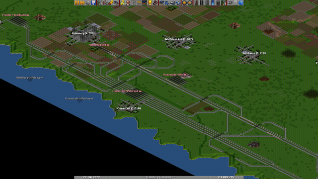 Screenshot of OpenTTD with an absolutely insane rail layout involving an insanely over-sized multi-platform train station for a small village and trying to make it interconnect in every way possible with the much thinner train track to the north