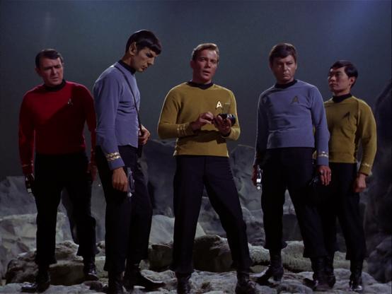 Scotty, Spock, Kirk, McCoy, and Sulu stand on a barren bluish landscape, ready to beam out.