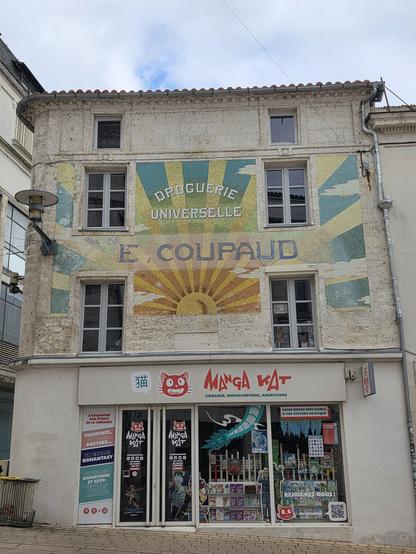 Photograph of the front of a shop showing an Art Nouvauex mural style name and a modern 'Manga Cat' sign with japanese character