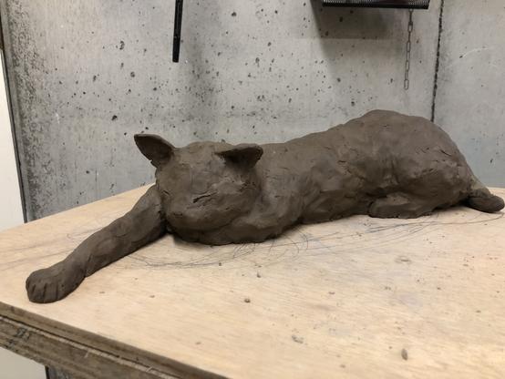 右前腕を前方にぴんと伸ばし、ほんのりと身体をカーブさせ、腹を床につけて眠る猫の塑像