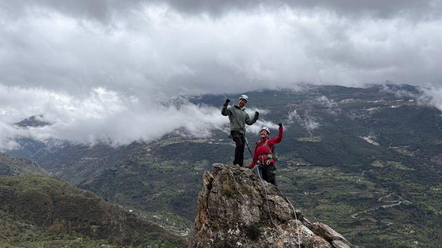 Two people enjoying a small rocky summit on a via ferrata